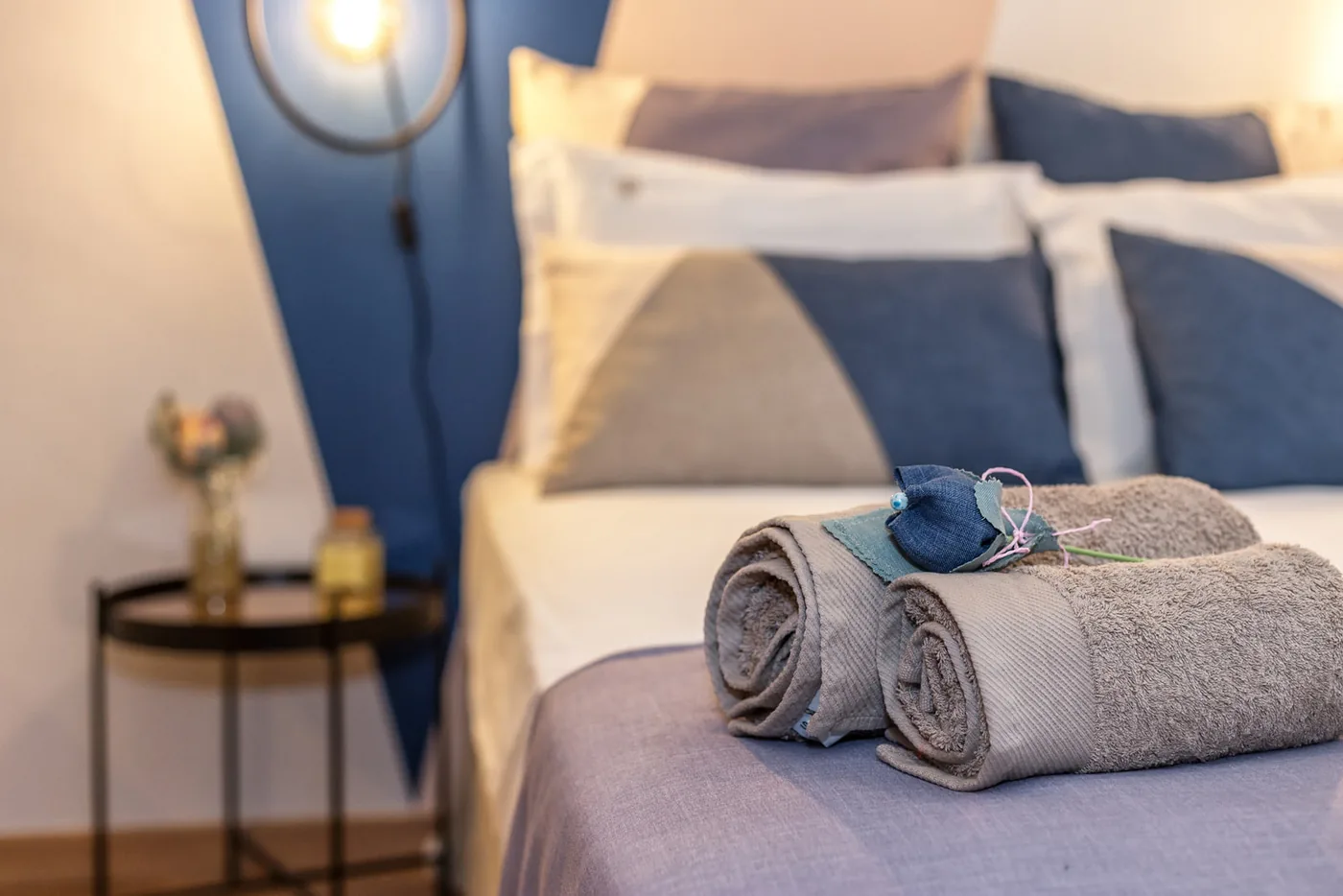 Rolled white towels laid on a freshly made bed with white linen